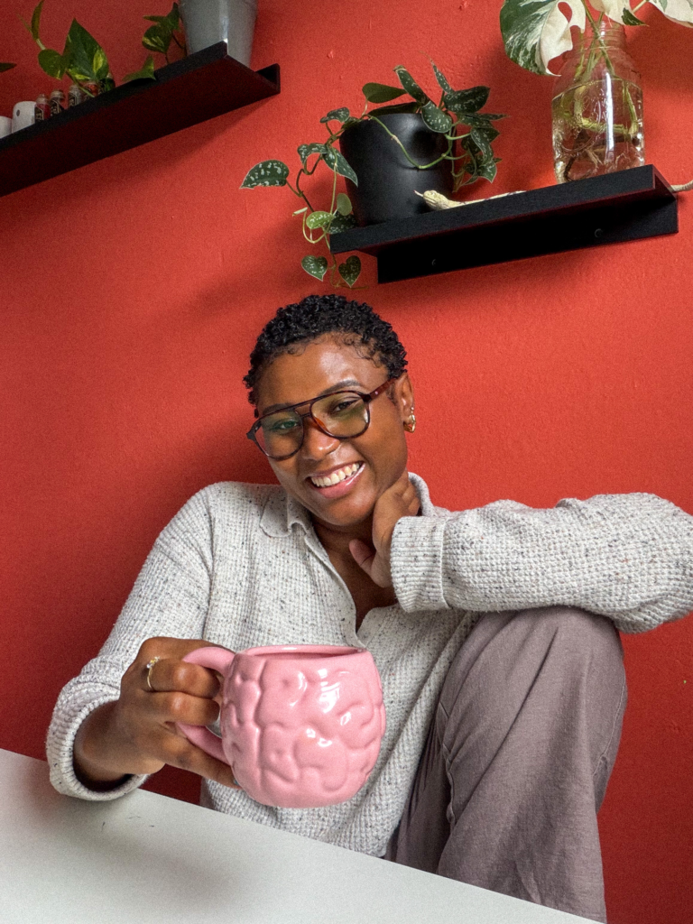 Brianne smiling and holding a pink brain mug